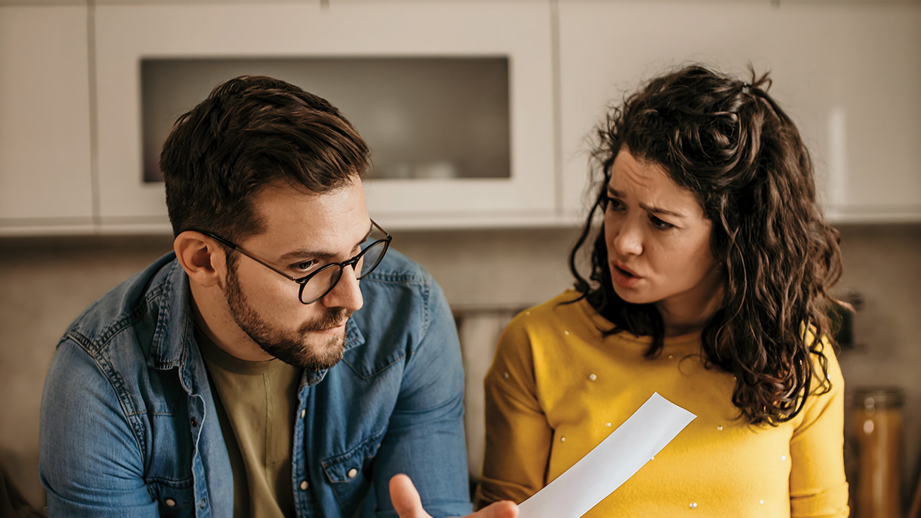 Jong stel hangend aan een keukenblad met enveloppen in hun hand voor een laptop